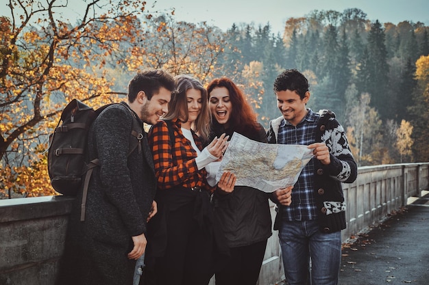 group-young-people-are-looking-map-where-they-are-while-walking-autumn-forest_613910-15159